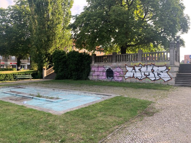 Foto der Wasseranlage auf dem Platz, im Hintergrund sind Treppen zu sehen