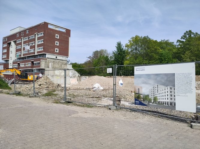 Foto zukünftige Stadtplatzfläche mit Bauzaun und Plakat mit Skizze Stadtplatz