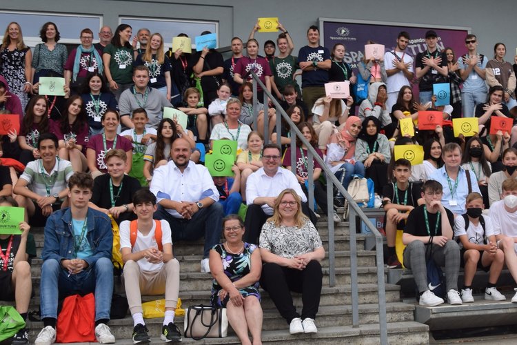 Jugendliche sitzen auf Stufen und halten Schilder hoch