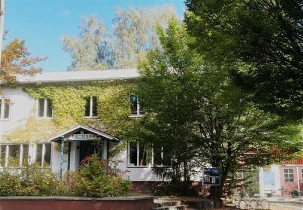 Foto des Dachsbaugebäudes und Teile der Außenanlage mit Bäumen