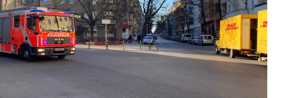 Feuerwehrauto und Postauto auf Kreuzung im Körnerkiez
