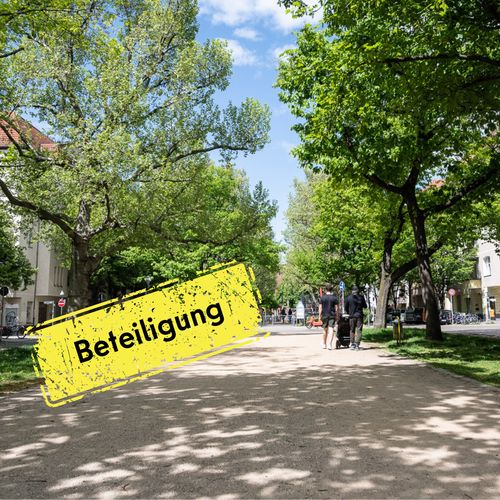 eine von Bäumen gesäumte Promenade auf der zwei Menschen einen Kinderwagen schie