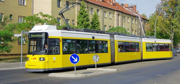 Das Bild zeigt links eine Straßenbahn im Vordergrund vor einer Häuserzeile